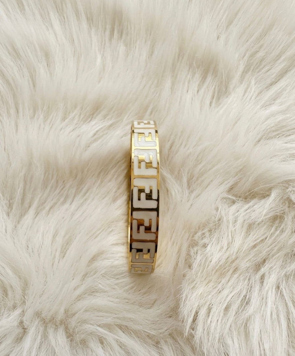 “Elegant gold bangle with a subtle cross charm – simple sophistication on your wrist"