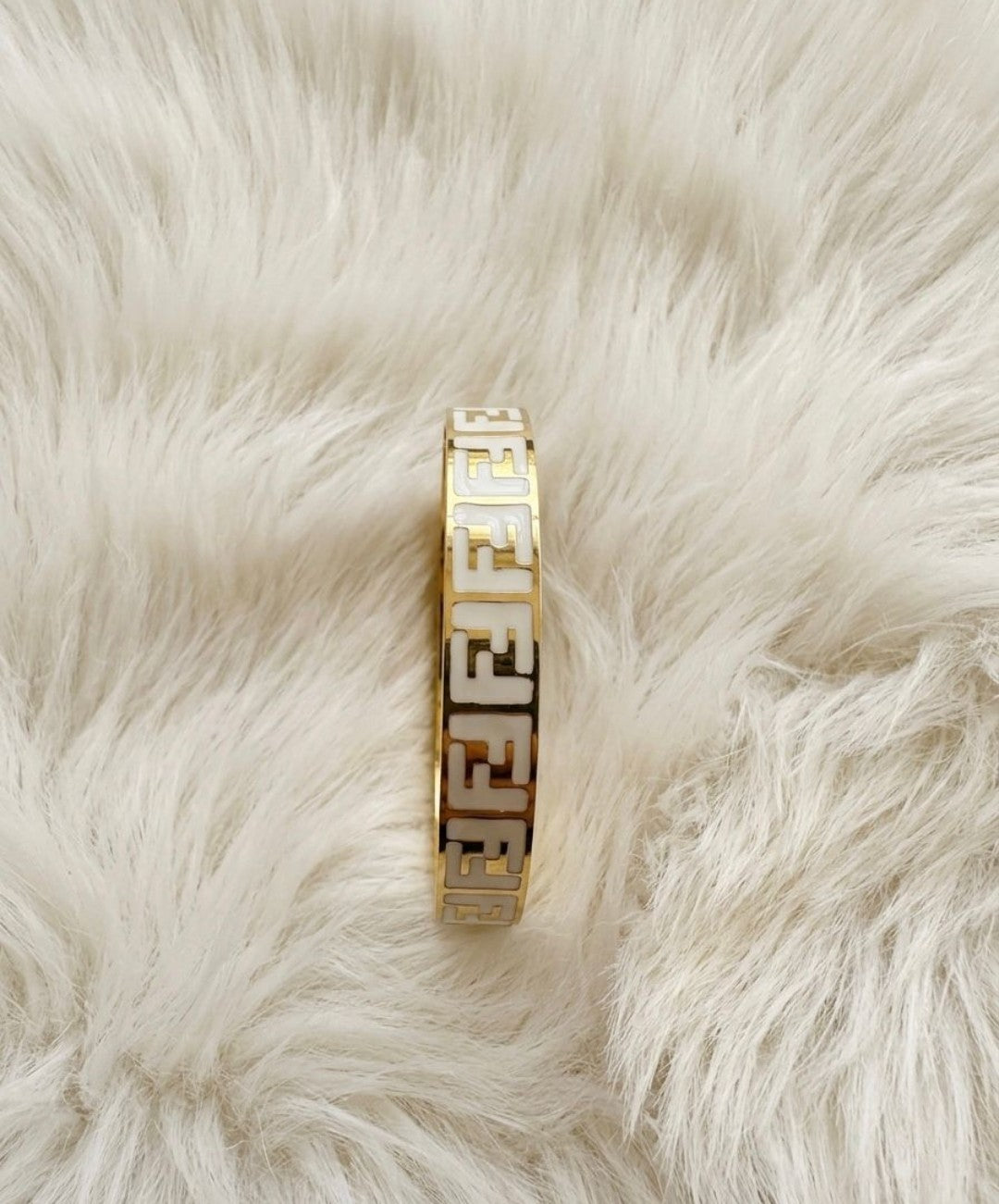 “Elegant gold bangle with a subtle cross charm – simple sophistication on your wrist"