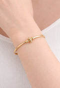 “Elegant gold bangle with a delicate cross charm, turning everyday style into timeless luxe"