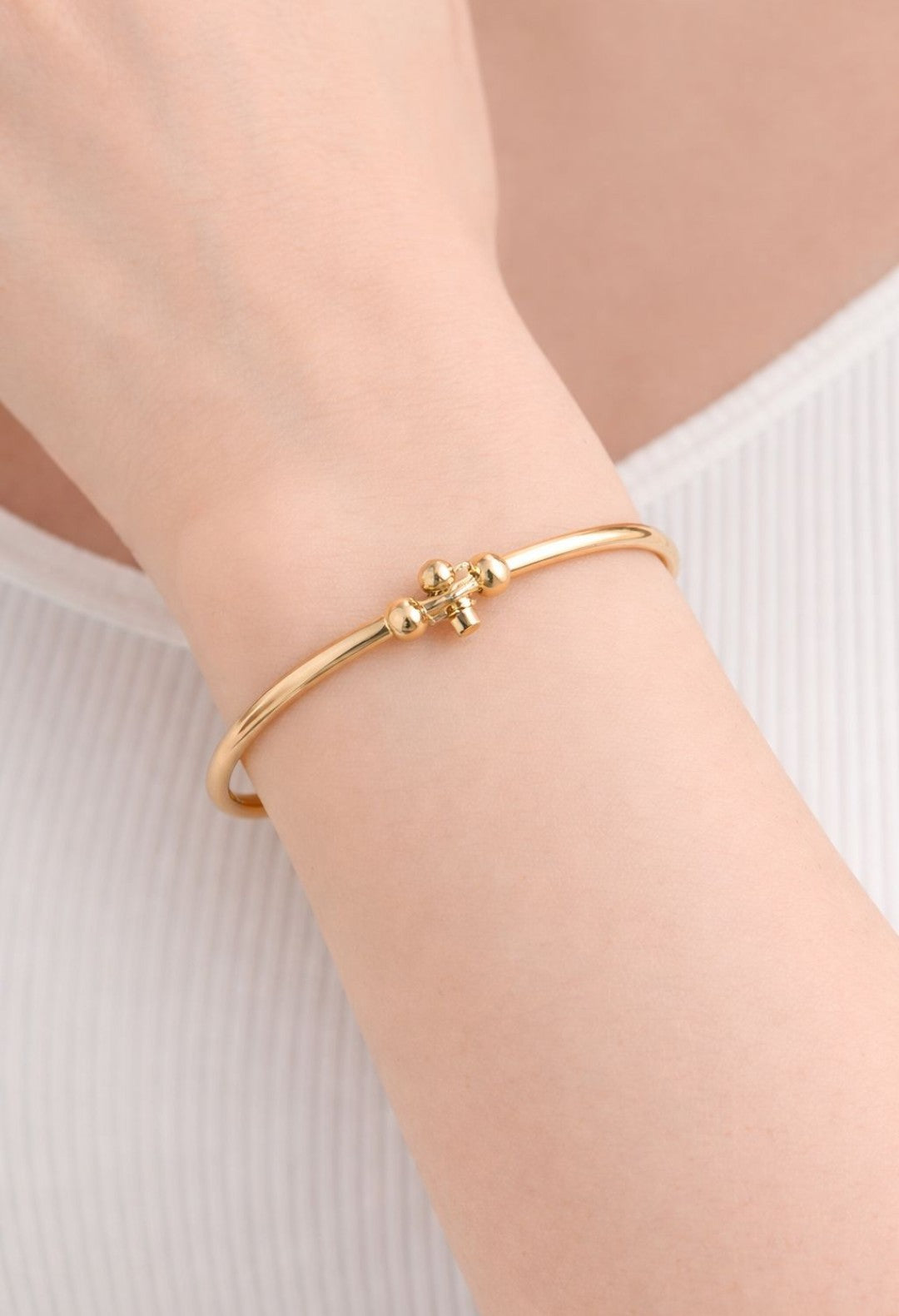 “Elegant gold bangle with a delicate cross charm, turning everyday style into timeless luxe"