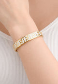 “Elegant gold bangle with a subtle cross charm – simple sophistication on your wrist"